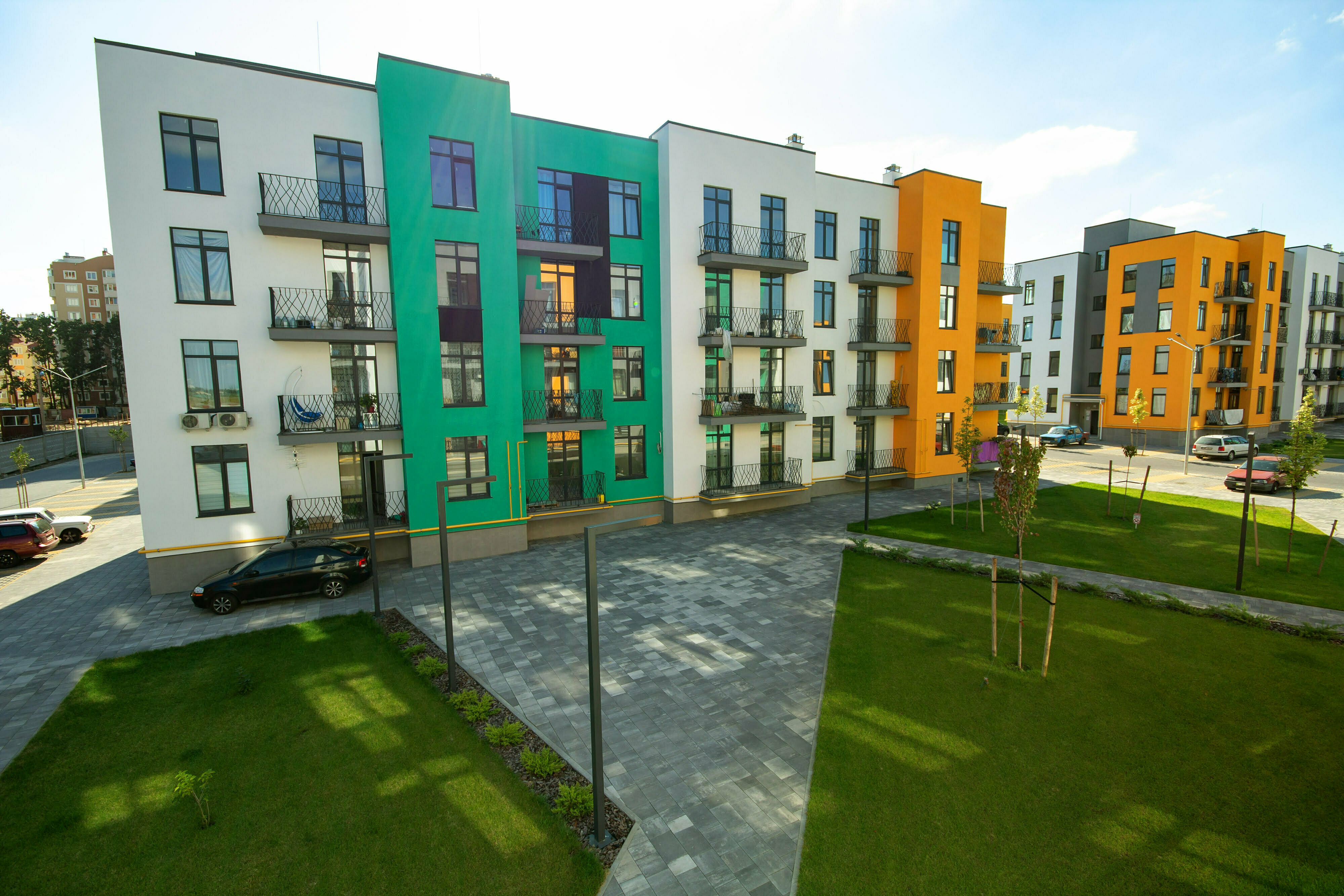 Yard between residential apartment buildings with green grass lawns and modern flat housing. Real estate development.